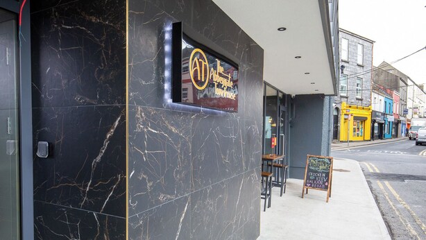 Un restaurante con fachada de mármol y terraza.