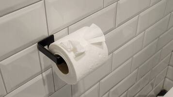 A toilet paper holder mounted on a tiled wall in a bathroom.