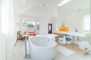 A modern bathroom with a large bathtub, a wooden vanity, and a large mirror. - West Hamptons Zen Retreat (Westhampton)