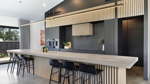 Una cocina moderna con una isla central, taburetes de bar y una planta decorativa.