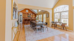 A spacious kitchen with a central island, wooden cabinets, and large windows.