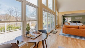 A spacious living room with large windows, a wooden floor, and a cozy orange sofa.