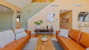 A spacious living area with a staircase, two leather sofas, a coffee table, and a bench.