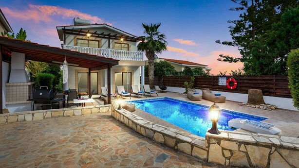 Ein zweistöckiges Haus mit Pool, Steinterrasse und Sitzbereich im Freien.
