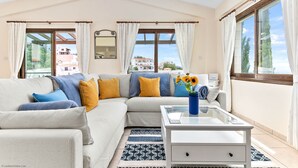 Ein modernes Wohnzimmer mit einer Couch, einem Couchtisch und Blick auf Gebäude.