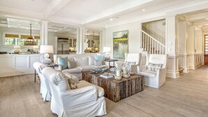 A spacious living room with a large sectional sofa, a coffee table, and a staircase leading to another level.