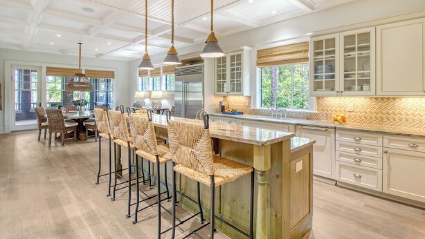 A spacious kitchen with a central island, bar stools, and a dining area with a round table and chairs.