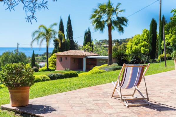 Une vue sur la plage avec un palmier, un petit bâtiment et une chaise de plage sur un chemin pavé.