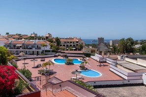 Ein Resort mit zwei Schwimmbecken, einer Dachterrasse und Blick aufs Meer.