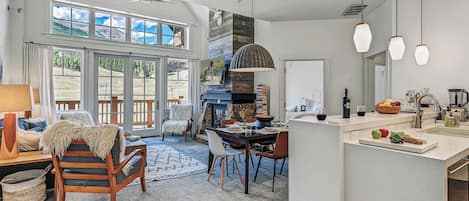 Amplia sala de estar con chimenea, mesa de comedor y vistas al exterior.
