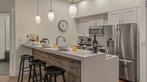Una cocina moderna con una isla central, electrodomésticos de acero inoxidable e iluminación colgante.