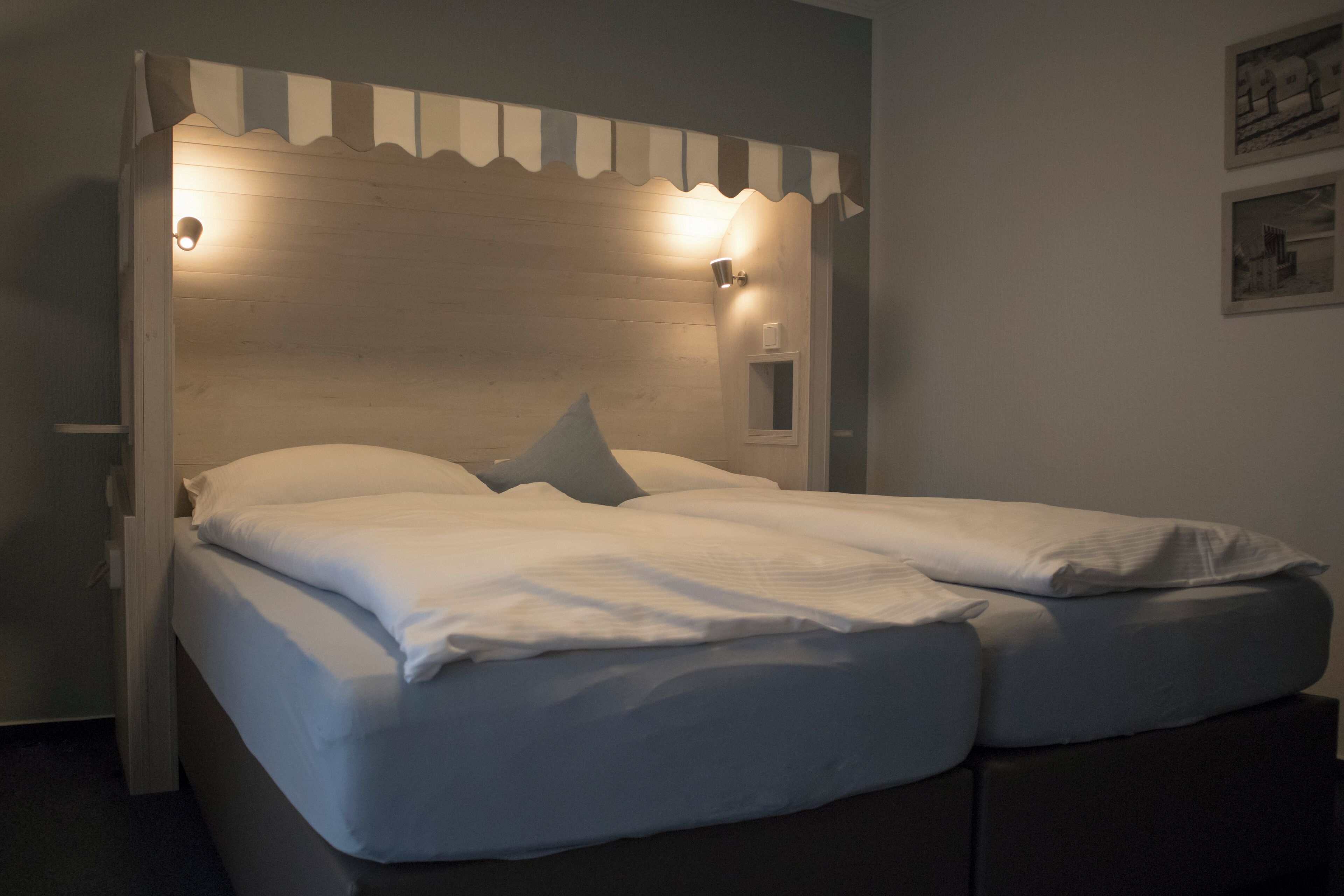 A bed with a wooden headboard, two bedside lamps, and a small window.