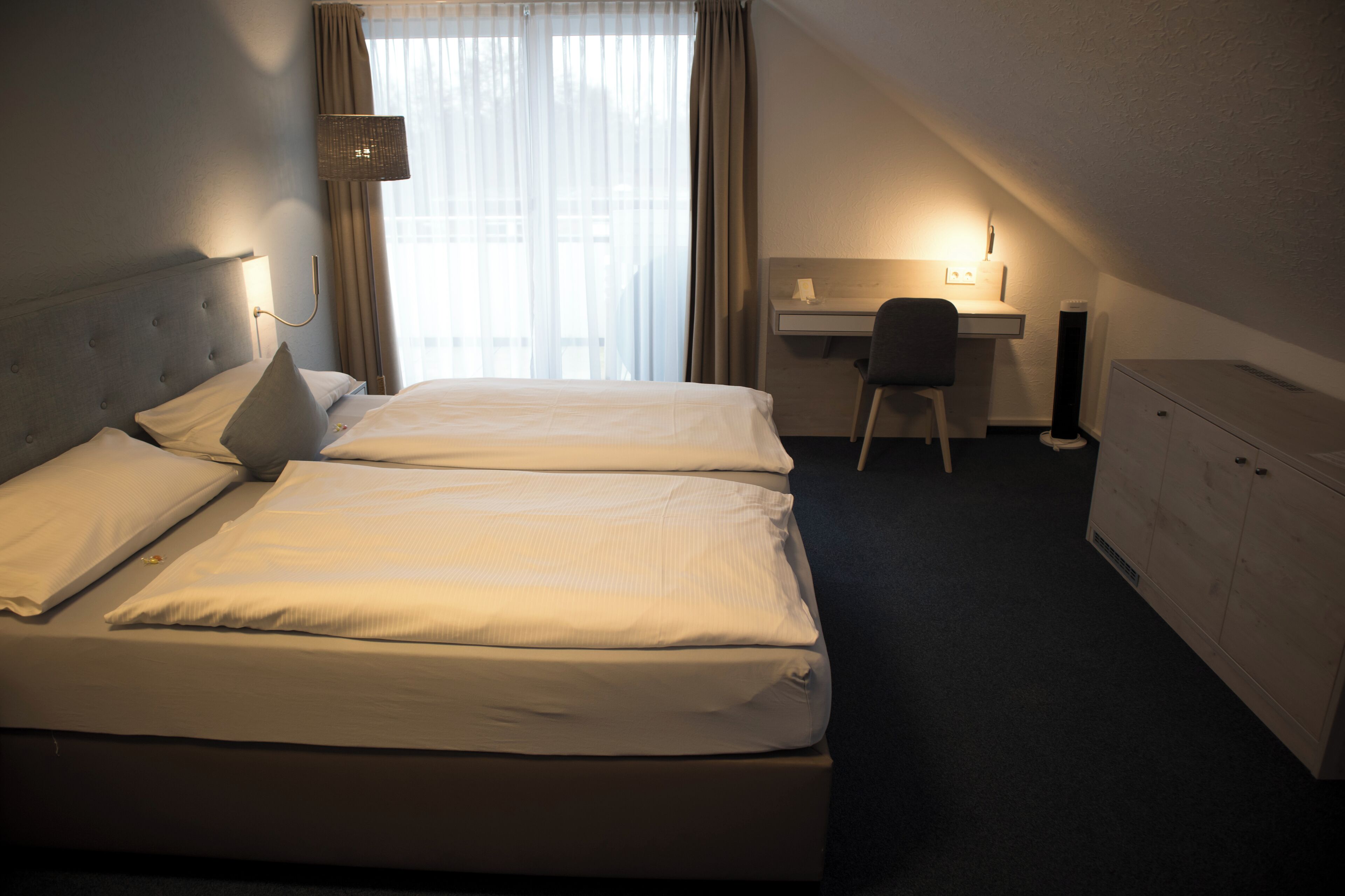 A hotel room with a double bed, a desk, a chair, and a wardrobe.