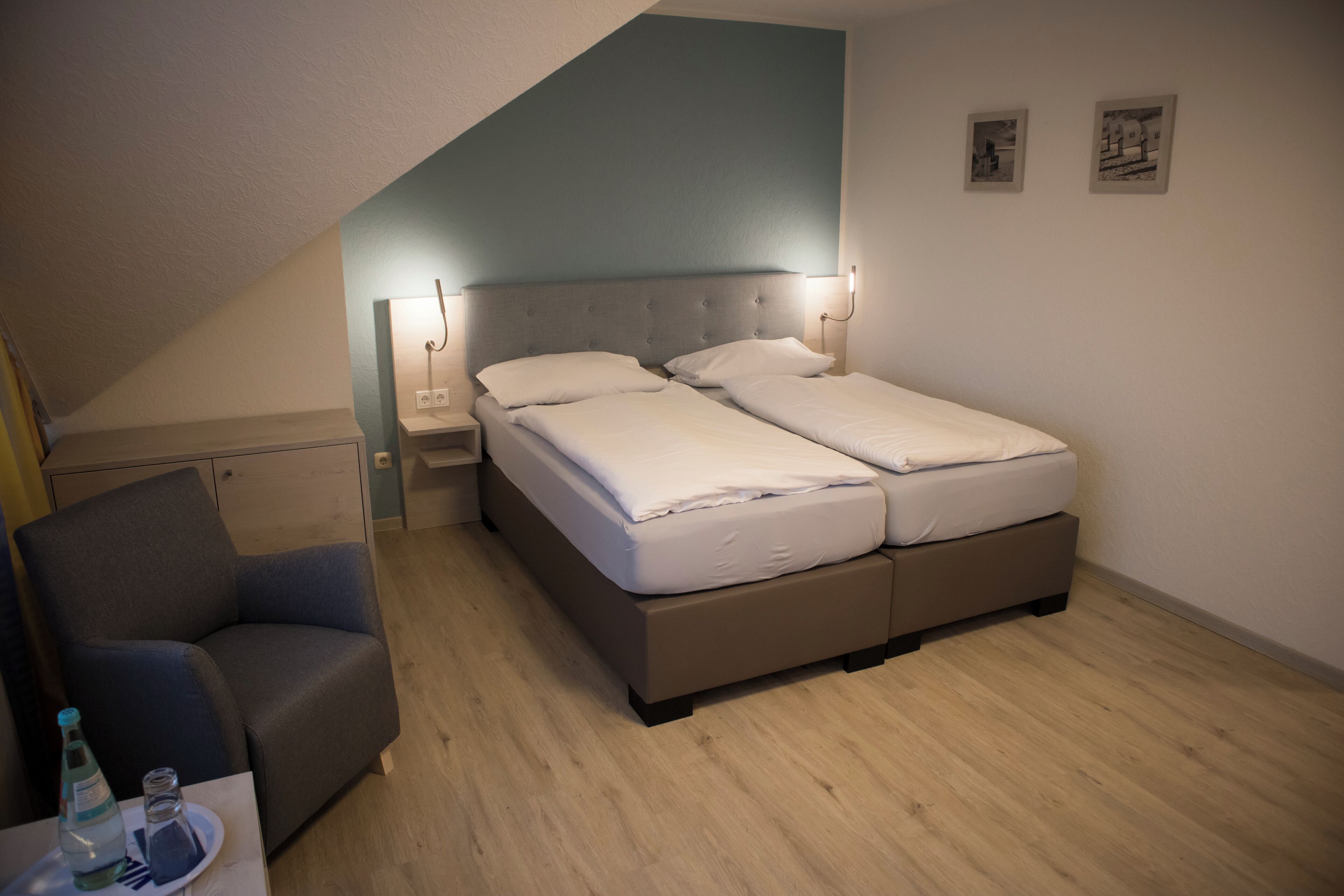 A bedroom with a bed, a chair, a nightstand, and a bedside table.