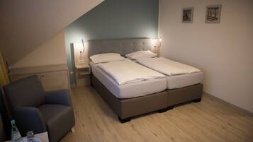 A bedroom with a bed, a chair, a nightstand, and a bedside table.