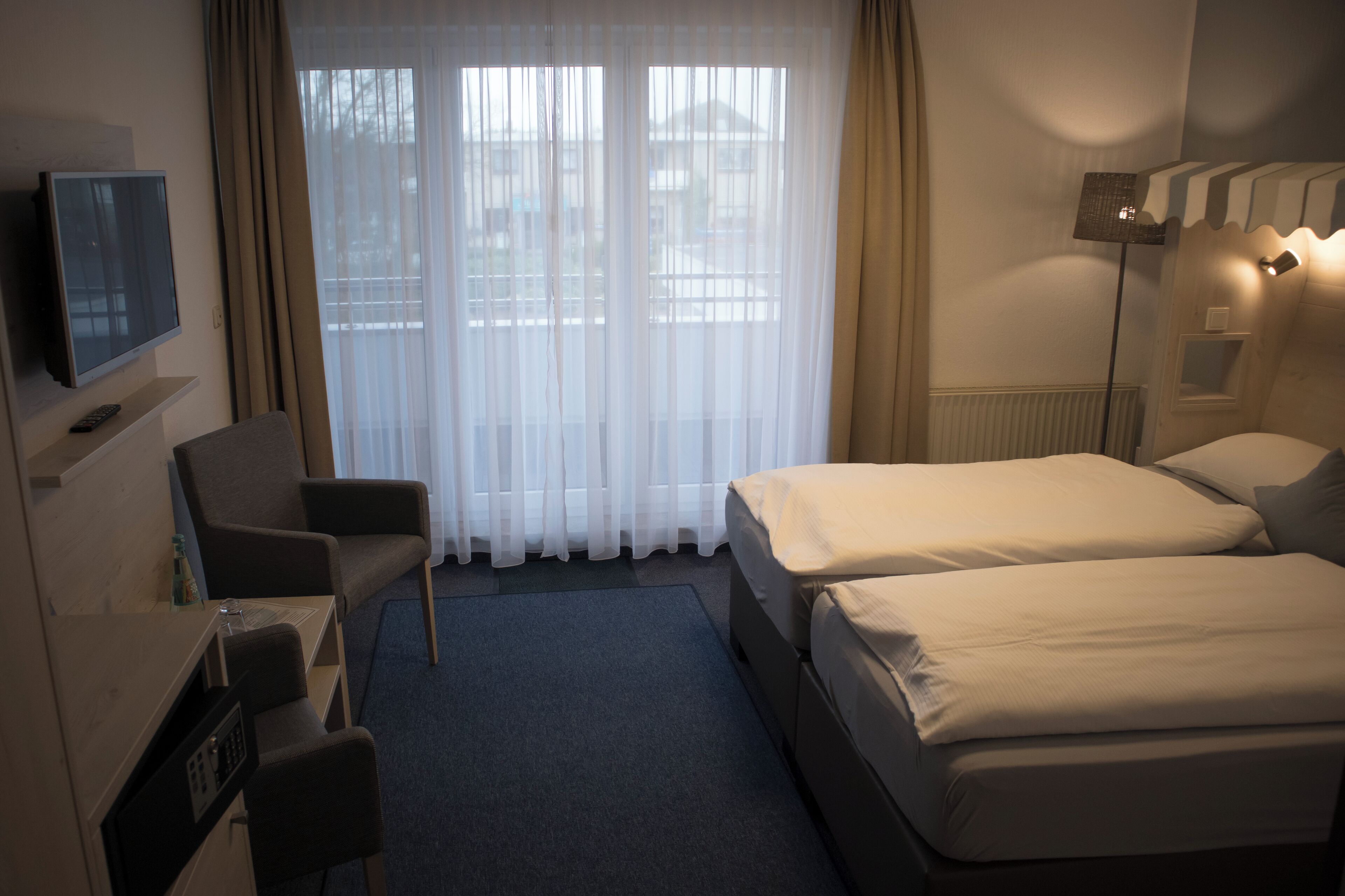 A hotel room with a TV, two beds, a desk, and a chair.