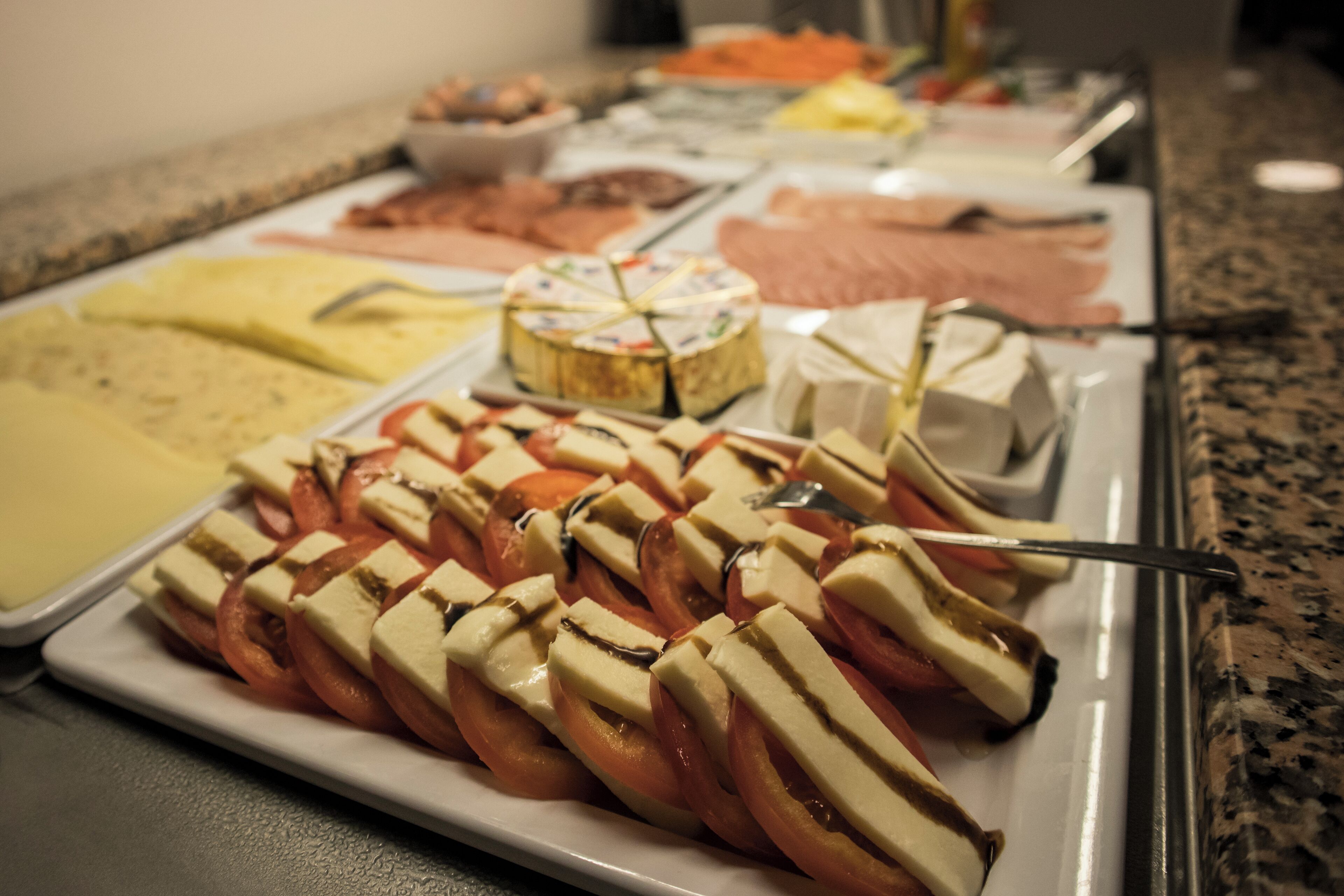 Un buffet proposant une variété d’aliments, notamment du fromage, des tomates et de la viande.