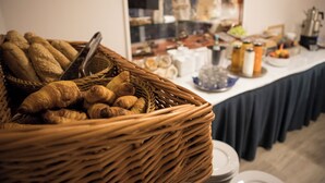 A breakfast buffet with a wicker basket filled with croissants and a variety of other pastries.