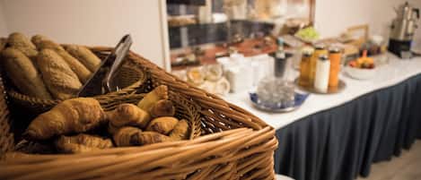 A breakfast buffet with a wicker basket filled with croissants and a variety of other pastries.