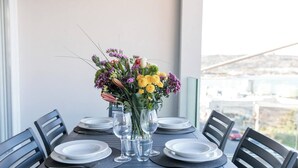 A table set for four with a vase of flowers, plates, and wine glasses.