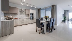 A modern kitchen with built-in appliances and a dining area with a table set for four.