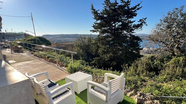 Une terrasse dotée de meubles blancs et offrant une vue sur le paysage.