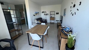 Un espace de vie moderne comprenant une table à manger, des chaises, un canapé, une bibliothèque, une horloge et une plante en pot.