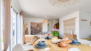 Uma área de jantar moderna com uma mesa redonda, louças azuis e um vaso de flores.
