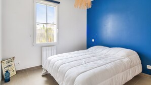 Quarto com uma cama grande, uma janela e uma parede azul.