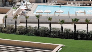 Un hôtel doté d’une piscine, de palmiers et offrant une vue sur la mer.