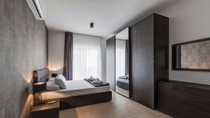 Une chambre d’hôtel moderne, équipée d’un lit, d’une table de chevet et d’un grand miroir.