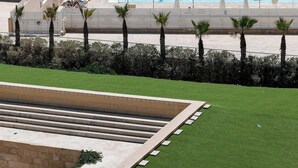 Un hotel con piscina, tumbonas y vistas al mar.