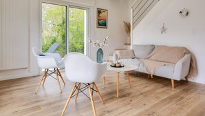 A modern living room with a sofa, two white chairs, a coffee table, and a staircase. - Discovering the Breton Riviera- House for 8 (La Forêt-Fouesnant)
