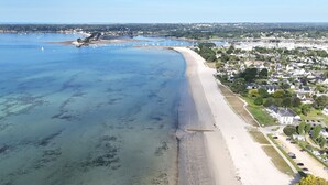 An aerial view of a coastal area with a sandy beach, a marina with boats, and residential buildings. - Discovering the Breton Riviera- House for 8 (La Forêt-Fouesnant)