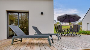 A wooden deck with two lounge chairs and a table with chairs. - Discovering the Breton Riviera- House for 8 (La Forêt-Fouesnant)