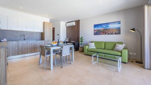 A modern kitchen with a dining area, a green sofa, and a painting on the wall.