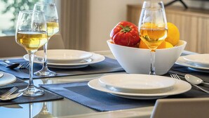 A dining table set with two wine glasses, plates, and a bowl of fruit.