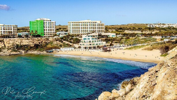 A coastal hotel with multiple buildings, a beach, and clear blue waters.