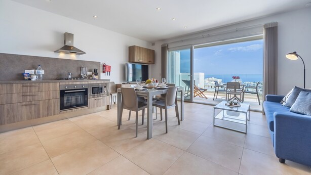 Un apartamento moderno con cocina, comedor y un balcón con vista a la ciudad.