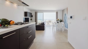 A modern kitchen with a gas stove, dark cabinets, and a large window overlooking a balcony.