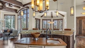A spacious kitchen with a large island, wooden beams, and pendant lighting. - Snow Meadow at The Colony (Park City)