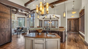 A spacious kitchen with a large island, wooden cabinetry, and pendant lighting. - Snow Meadow at The Colony (Park City)
