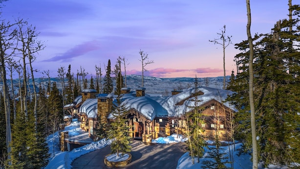A snow-covered lodge with multiple buildings, a central courtyard, and a mountainous backdrop. - Snow Meadow at The Colony (Park City)