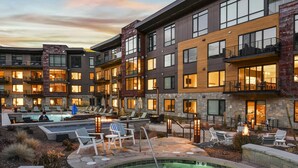 A modern hotel with a heated outdoor pool, lounge chairs, and a stone facade. - Lift Condo With Ski-in out w Village Access hot tub Fitness Center ski Rentals On-site (Park City)