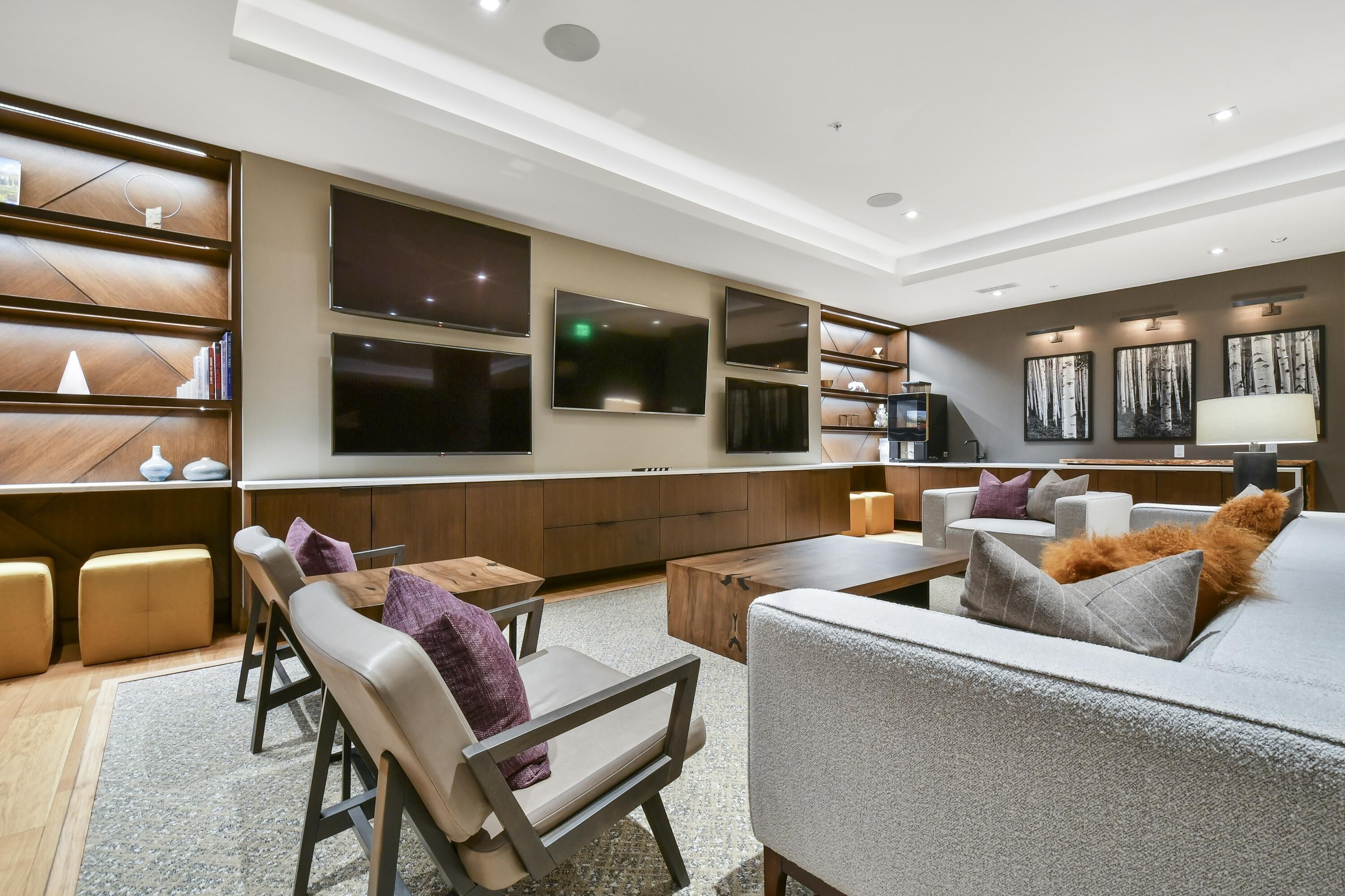 Una sala de estar moderna con un sofá, sillas, una mesa de centro y un televisor montado en la pared.