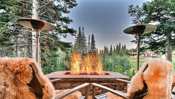 A patio with a fire pit, surrounded by chairs and a view of a forest. - Chic Colony Ski-in Ski Out Villa Direct Access to Adventures at Park City Resort Hot Tub Gym (Park City)