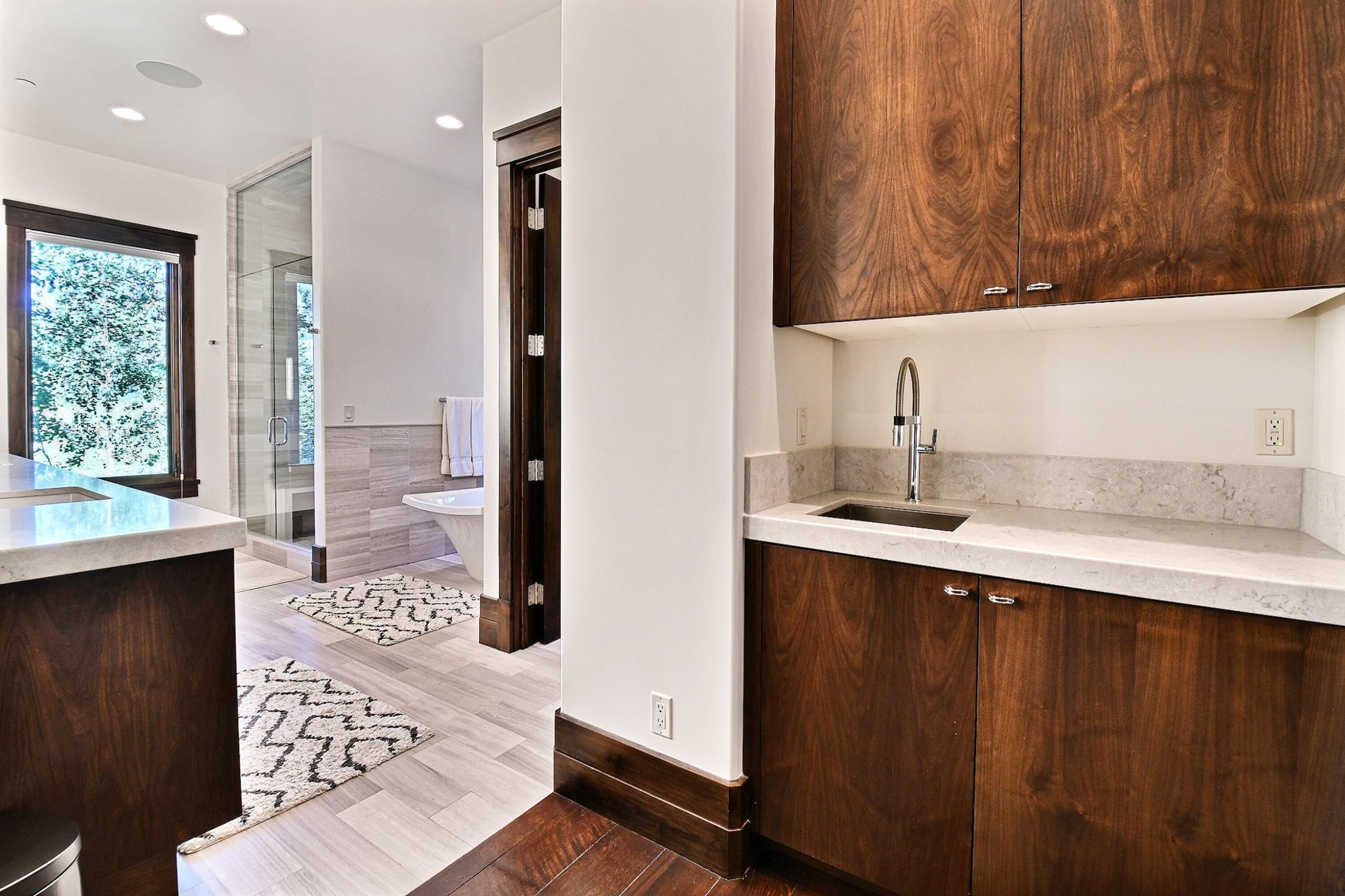 A modern kitchen with dark wood cabinets, a marble countertop, and a glass-enclosed shower area.