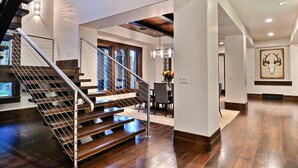 A modern interior with a wooden staircase, a dining area, and a large artwork on the wall. - Chic Colony Ski-in Ski Out Villa Direct Access to Adventures at Park City Resort Hot Tub Gym (Park City)