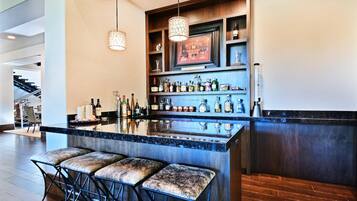 A modern bar area with a marble countertop, multiple liquor bottles, and bar stools.