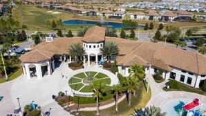 A large building with a central courtyard, surrounded by a golf course and a body of water. - Luxury 6BR Villa w/ Private Pool • Disney (Davenport)